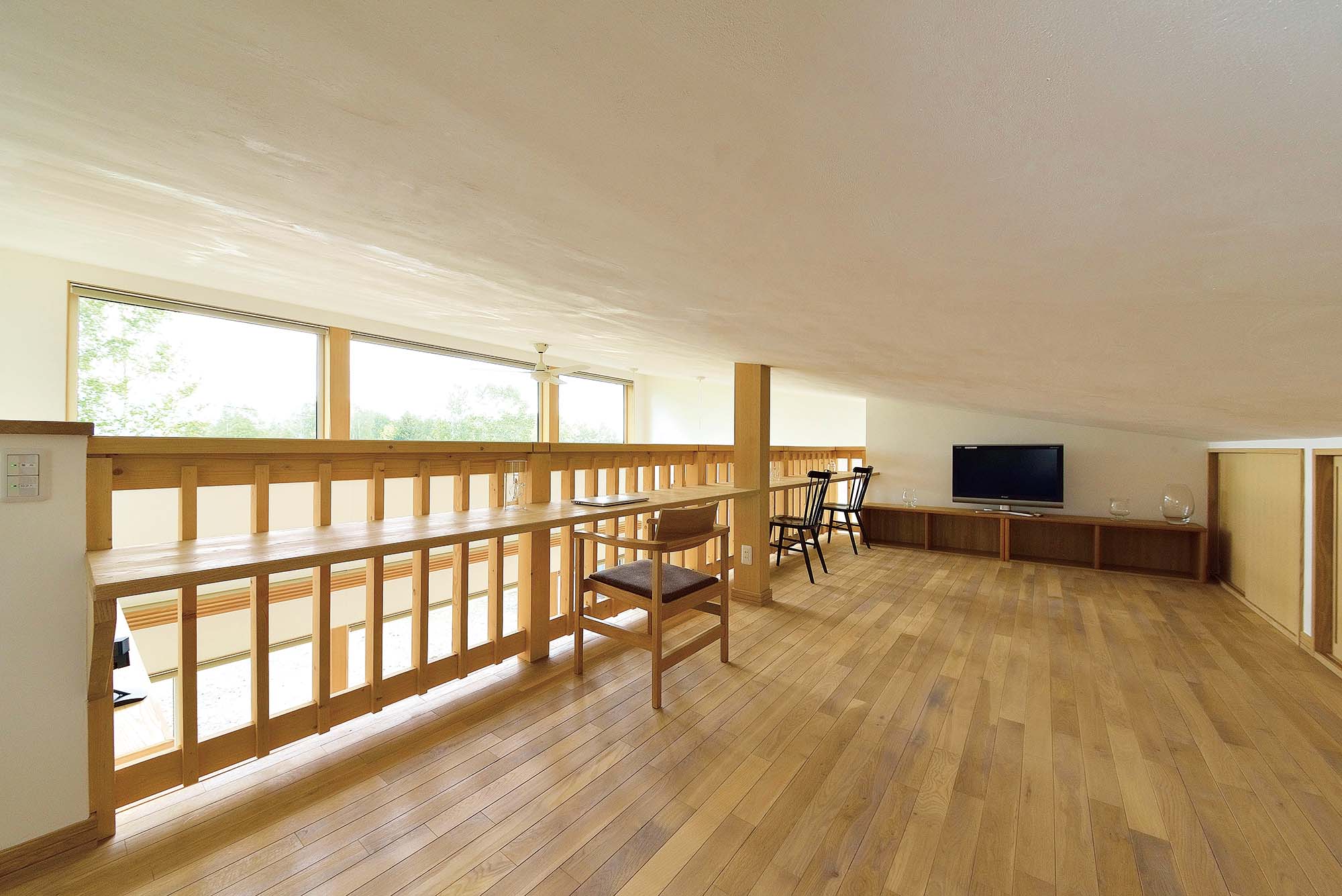 リビングから階段で結ばれたロフト。大きな窓越しに十勝岳が楽しめるタモ材の造作カウンターはKさんのお気に入り。ロフトは来客時の予備室も兼ねる