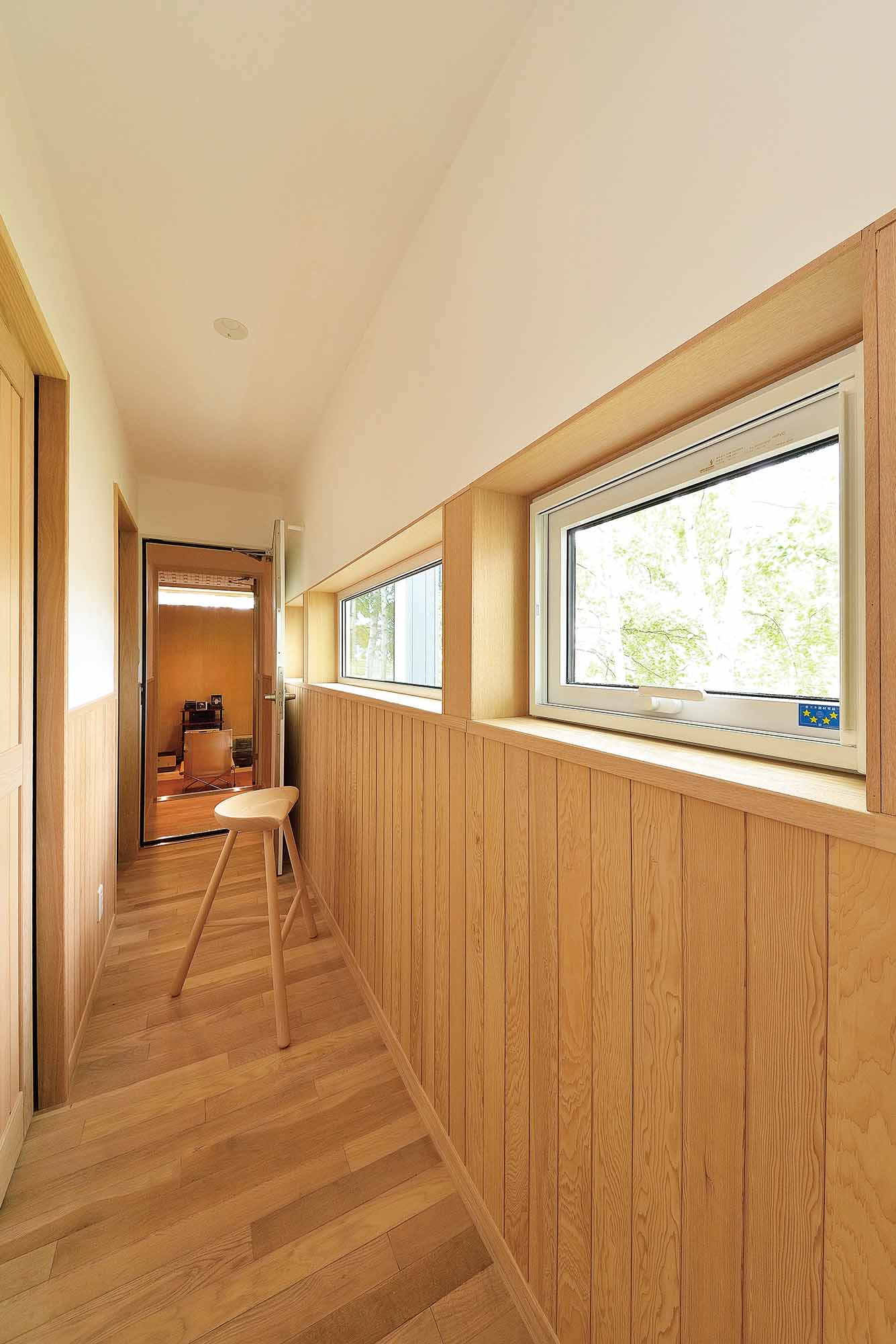 リビングから延びる音楽室への廊下。田園風景の中を走る列車が見える窓辺。左手には寝室がある