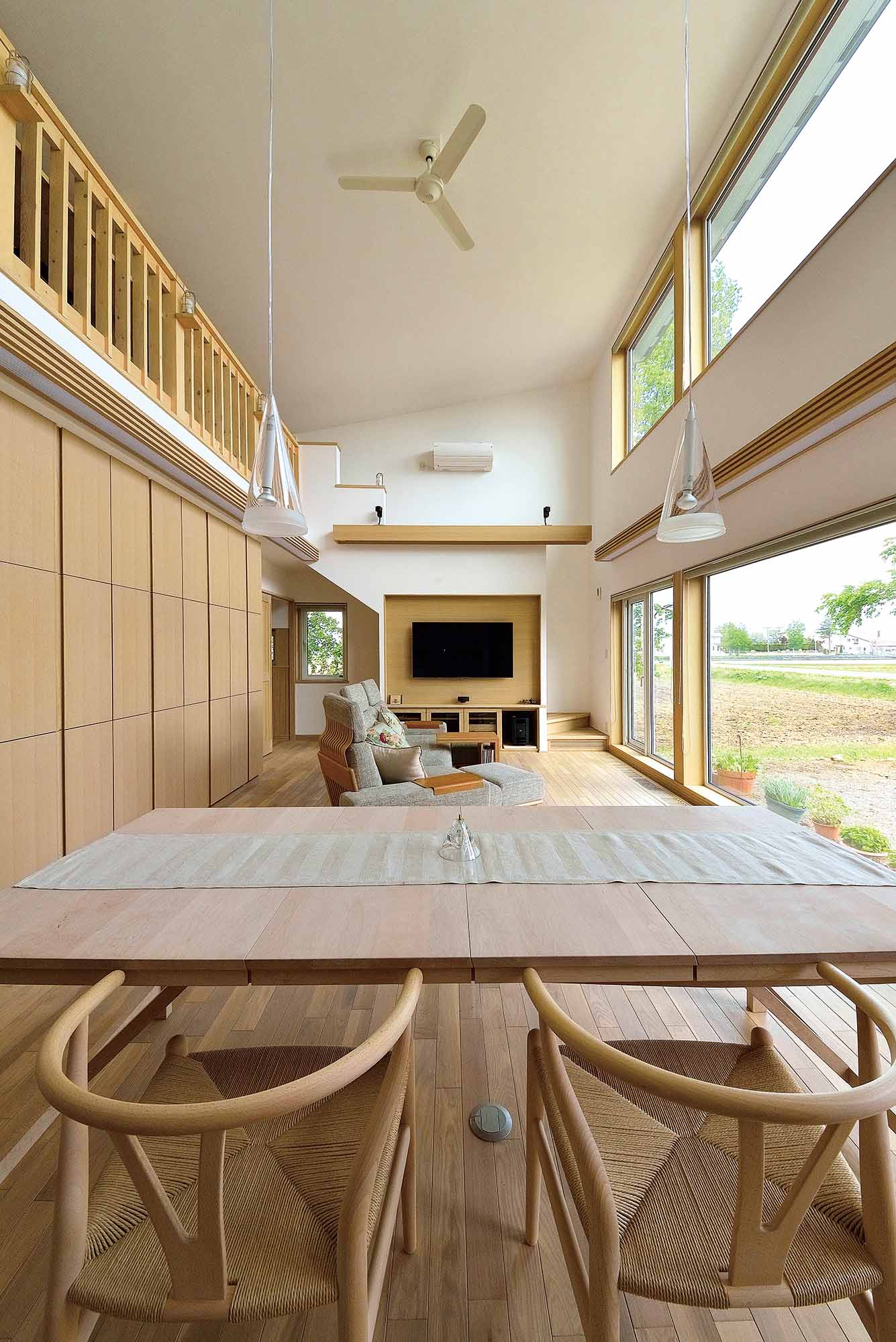 高い天井と大開口が伸びやかな空間をつくりだすリビング・ダイニング。ロフト下には、大容量の壁収納を造作。中央には仏壇も組み込まれている。テレビ上のスクリーンを下ろせば、シアタールームとしても活用できる