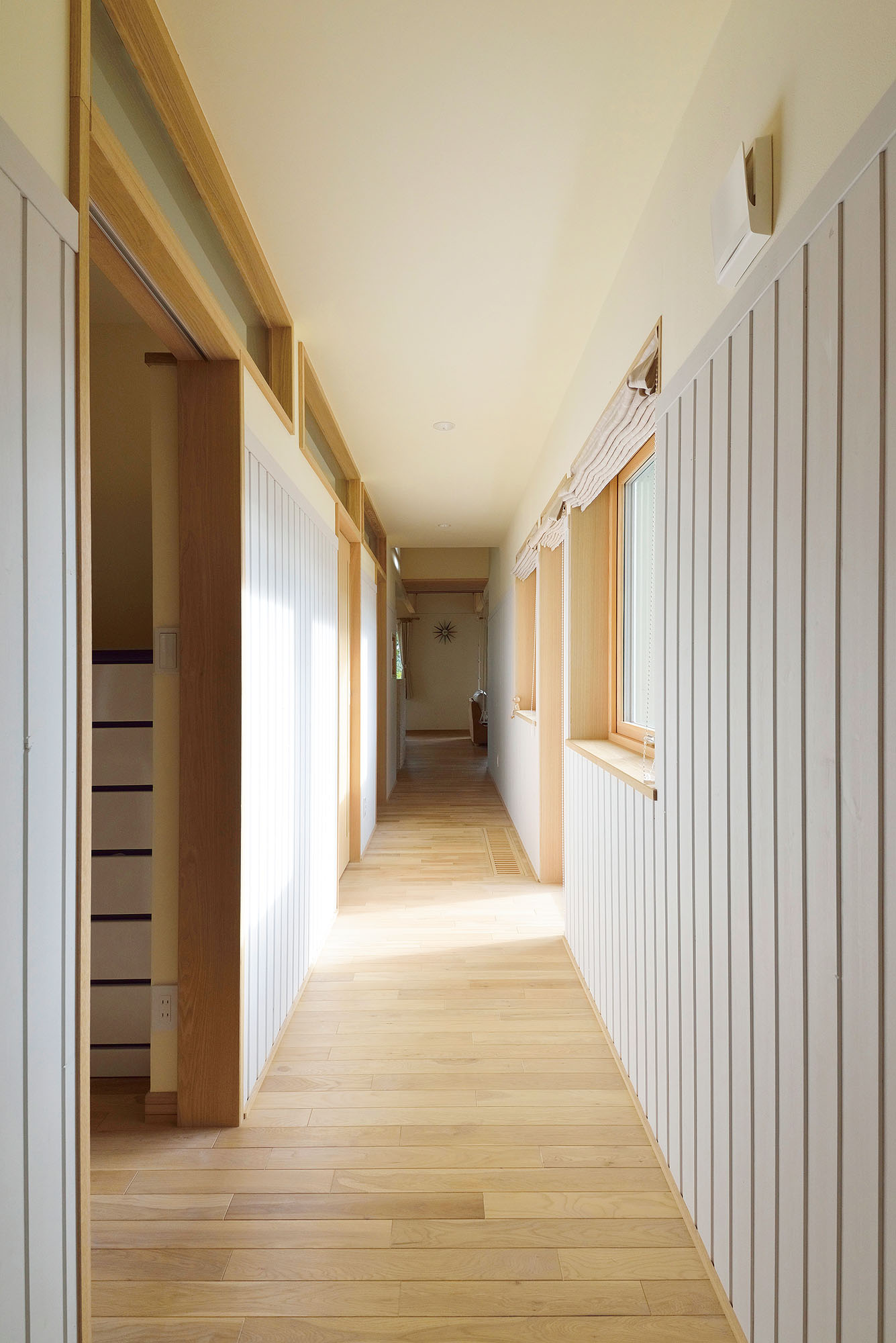 寝室ゾーンとLDKを結ぶ廊下には、パイン材を使用。廊下に並行して効率良い家事動線を確保した水まわりとウォークインクローゼットがレイアウトされている