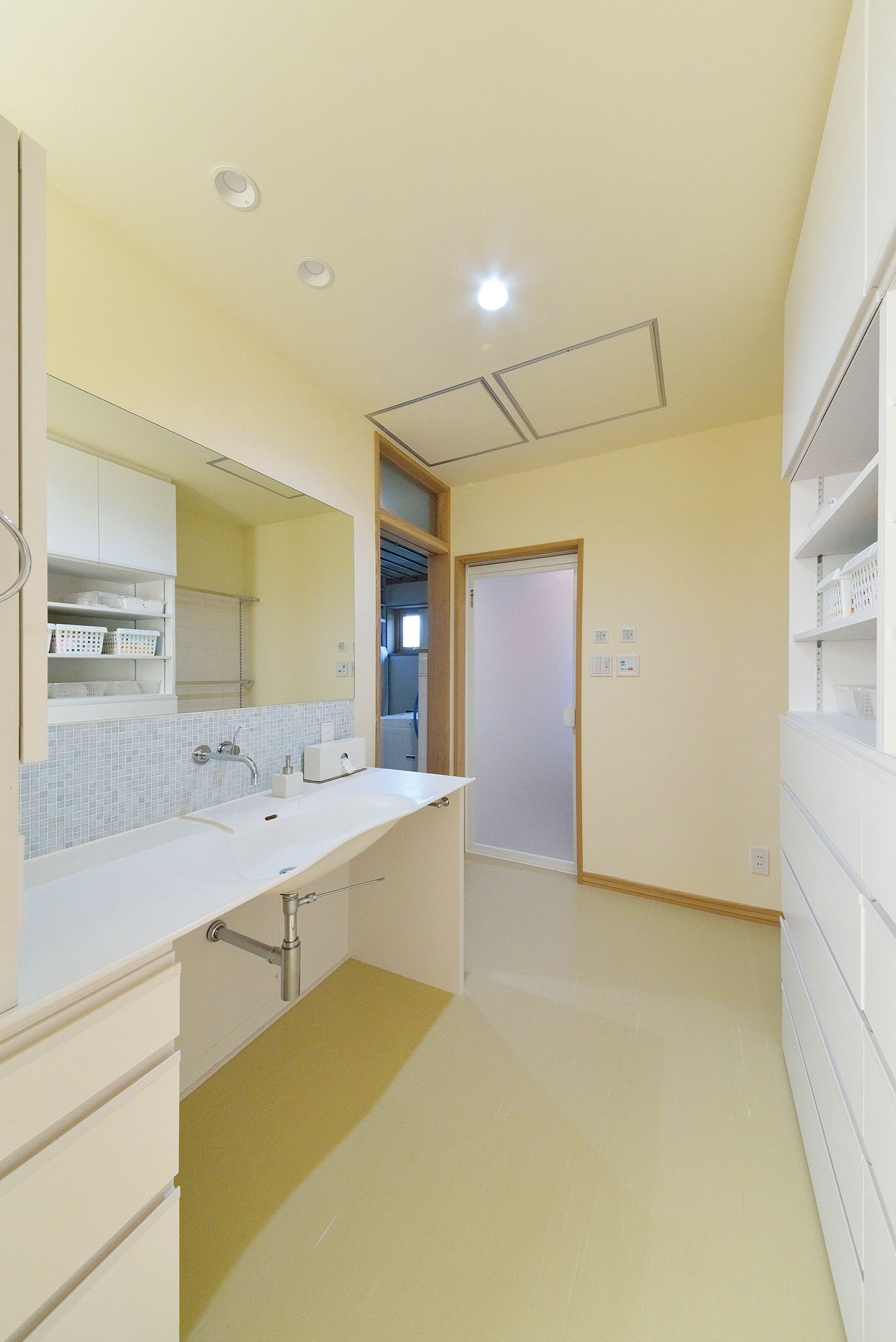 造作洗面台を備えたユーティリティ。タオルや下着類などを十分にしまえる収納を準備。洗濯室が隣接し、脱いだ衣服や使用済みのタオルはすぐに片付けられる。洗濯室には物干しスペースやスロップシンクも設置