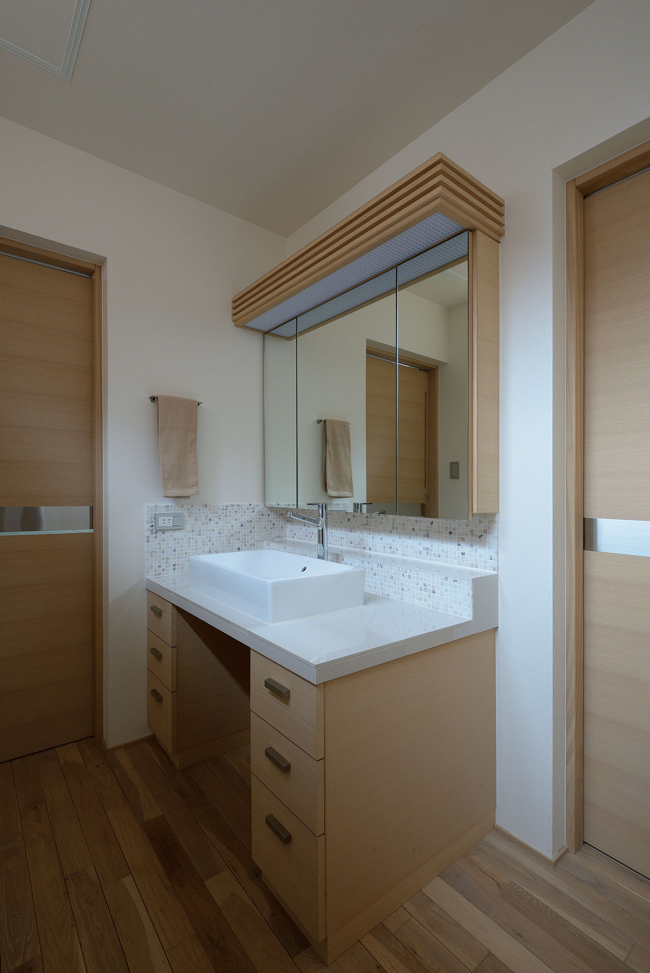 玄関から続く廊下の一角に設けられた洗面スペース。左はトイレ、右は浴室への扉