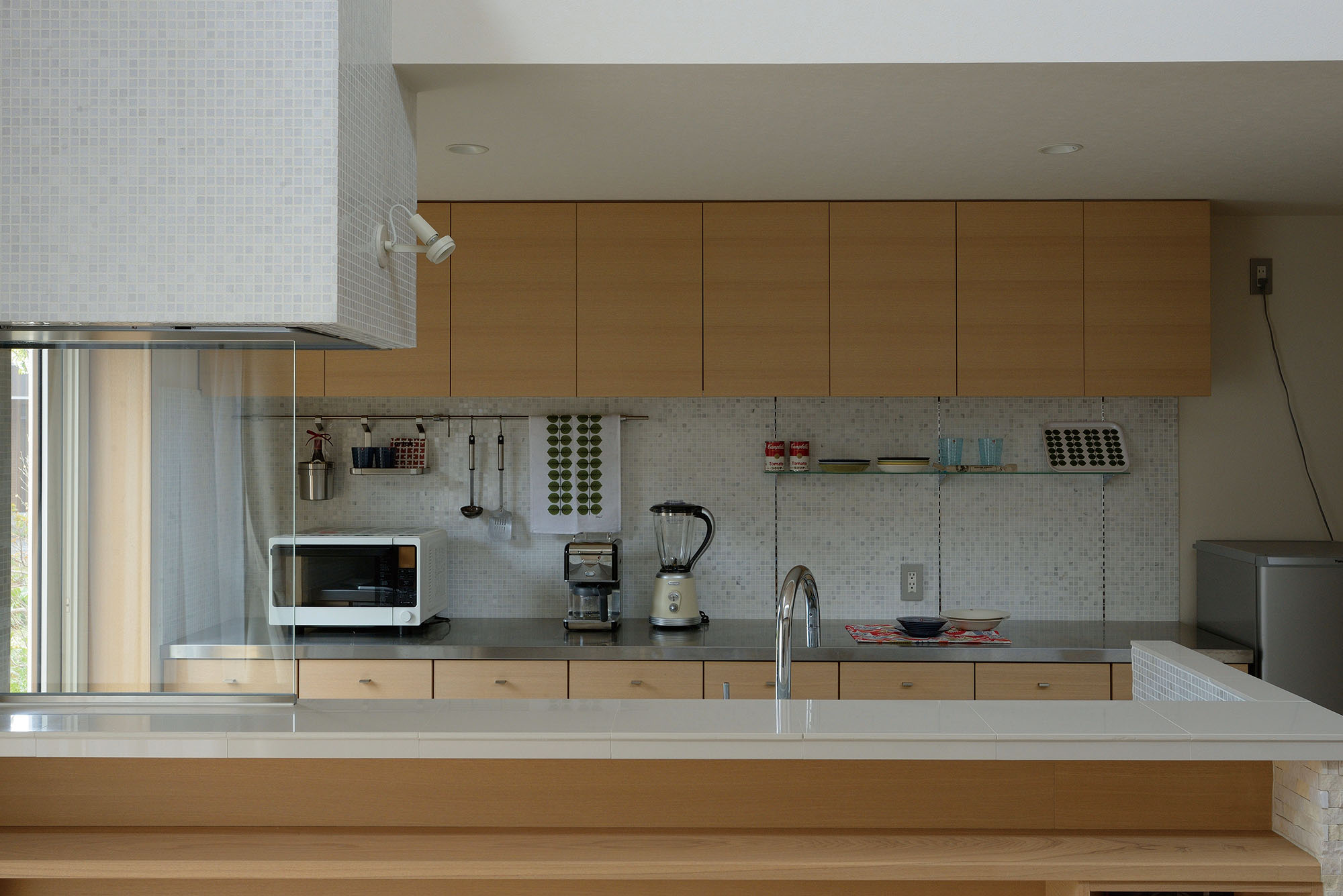 シンプルでオープンな対面キッチン。壁やフードはタイルで仕上げた