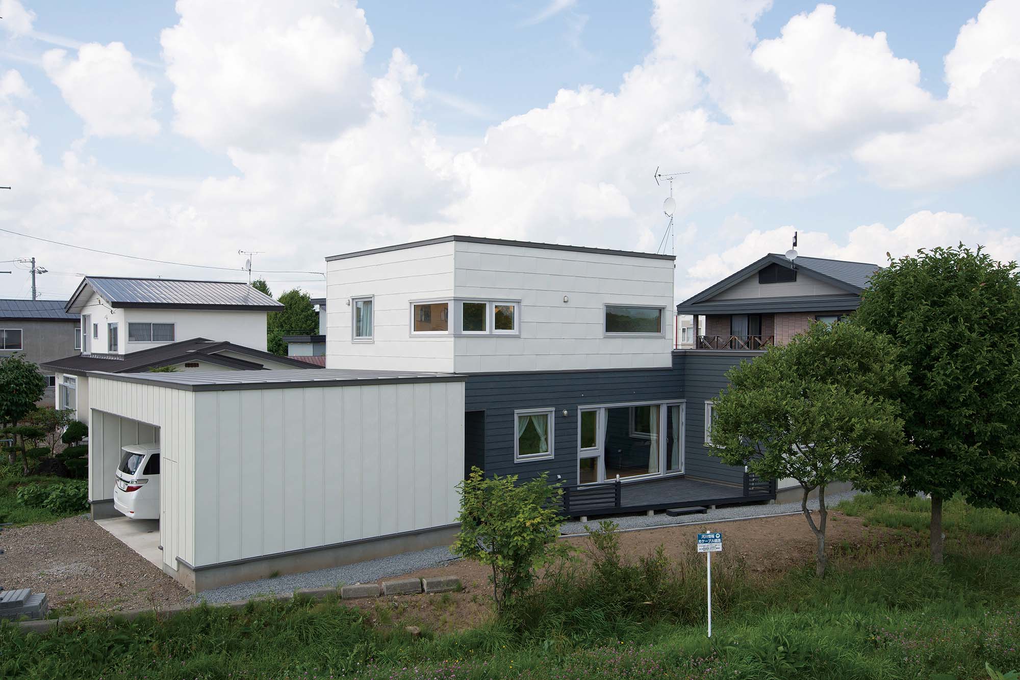 堤防に面して広がる庭にウッドデッキもある、眺望に恵まれた住まい