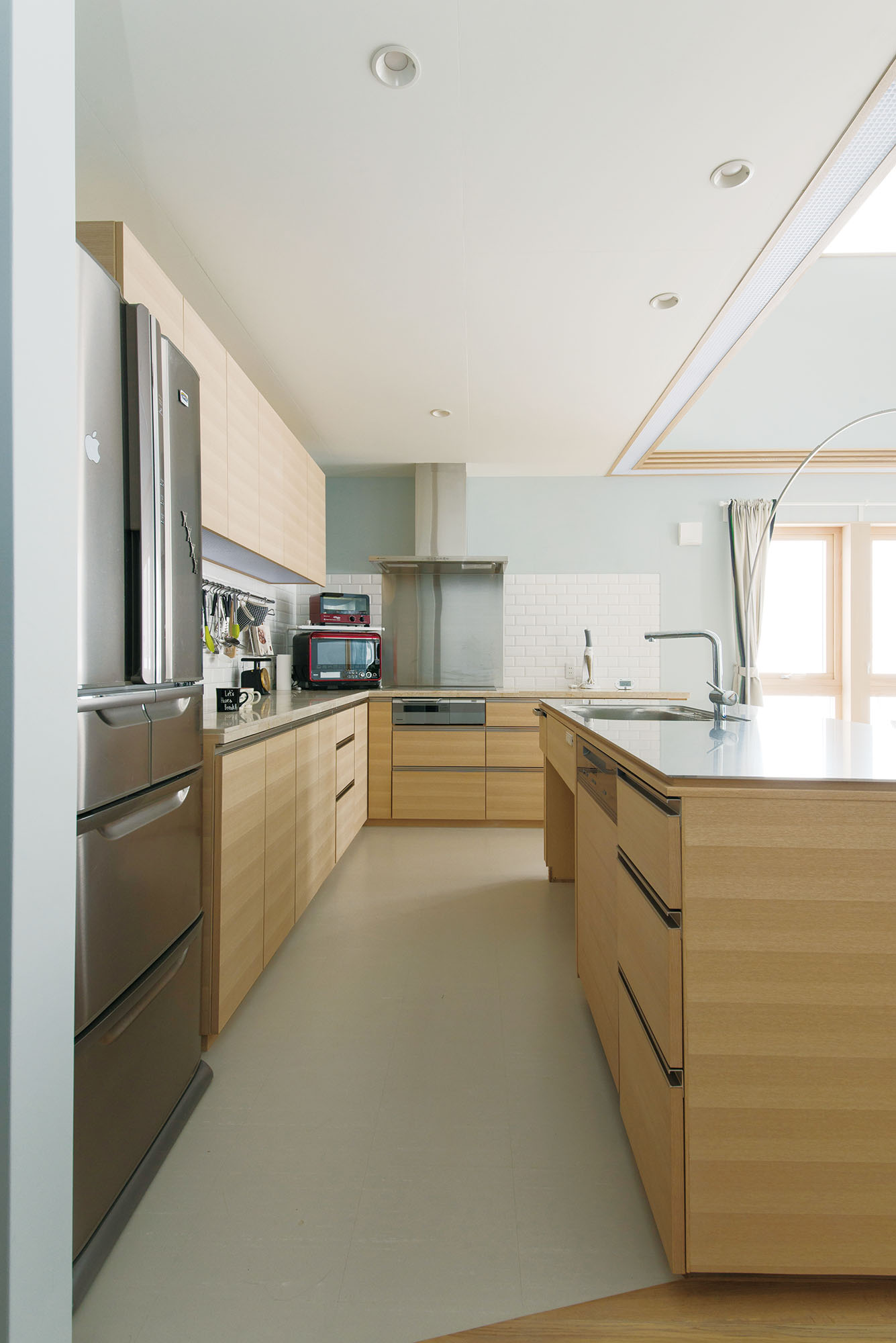 リビング・ダイニングを見渡せる造作キッチン。ご夫妻が一緒にキッチンに立てるよう通路は広く、アイランドも高めに設計