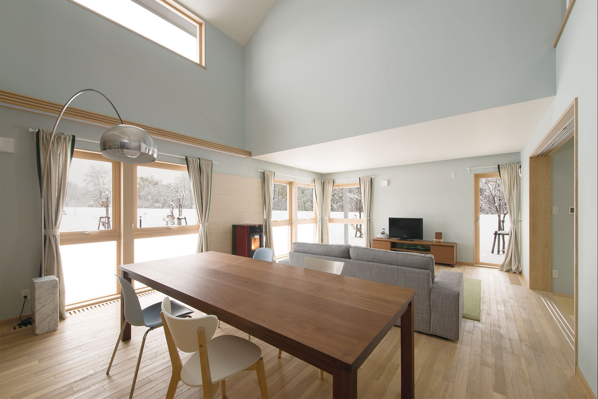 吹き抜けが心地よいダイニングには、多目的に利用できるウォールナット材の特注テーブルを設置